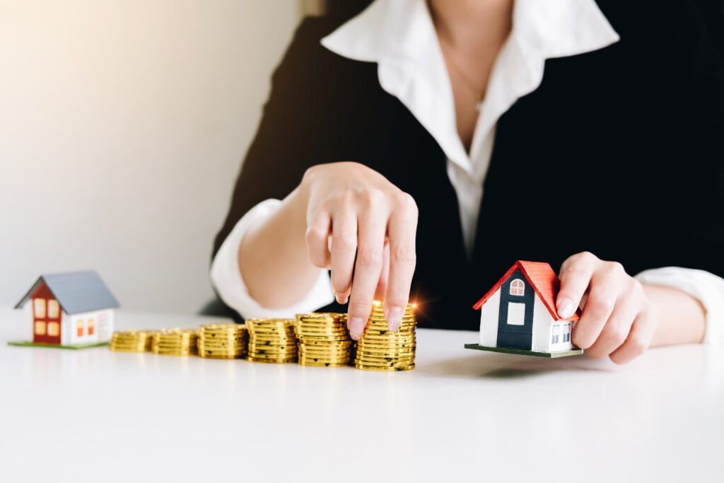 businesswoman-is-holding-house-models-and-coins-co-2022-11-11-04-27-48-utc