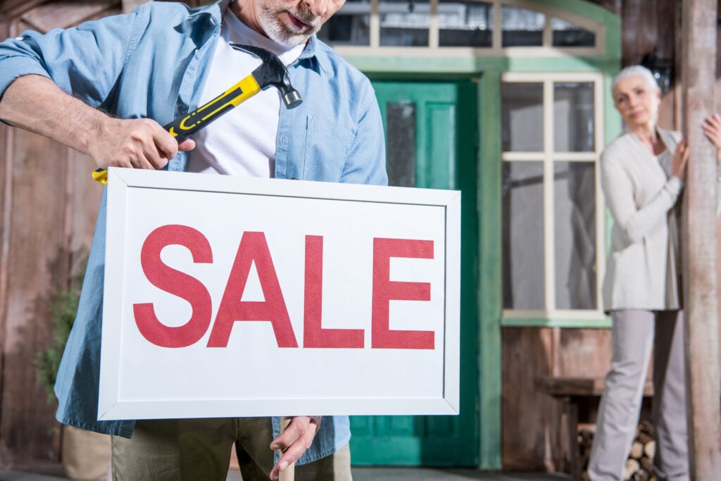 close-up-of-sale-sign-senior-couple-selling-their-2022-12-16-18-53-47-utc