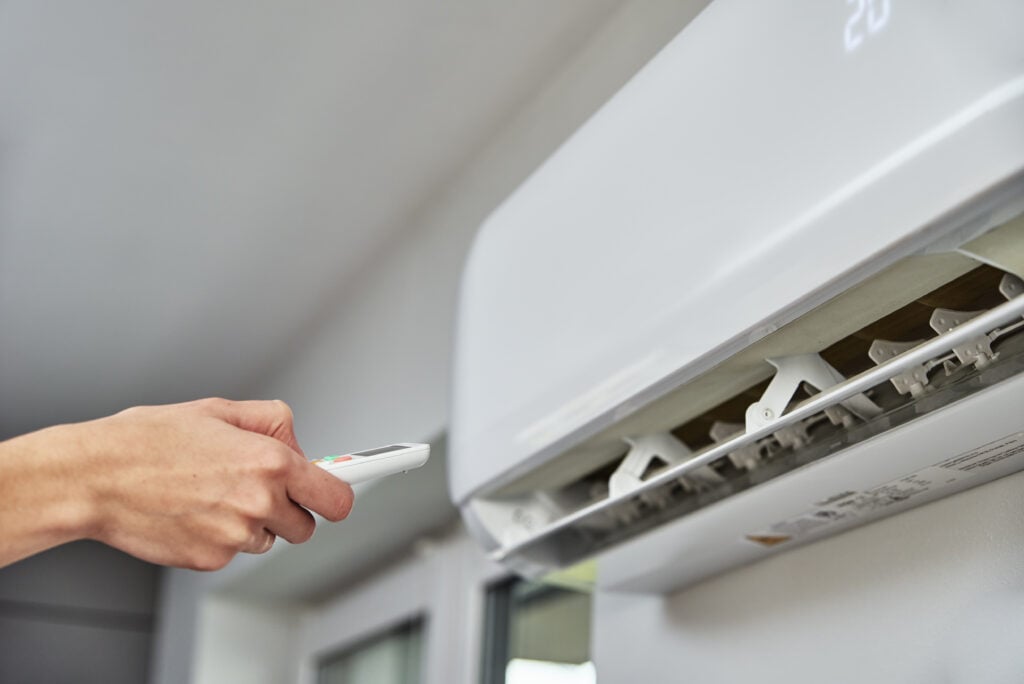 hand-adjusting-temperature-on-air-conditioner-2022-12-16-12-51-09-utc