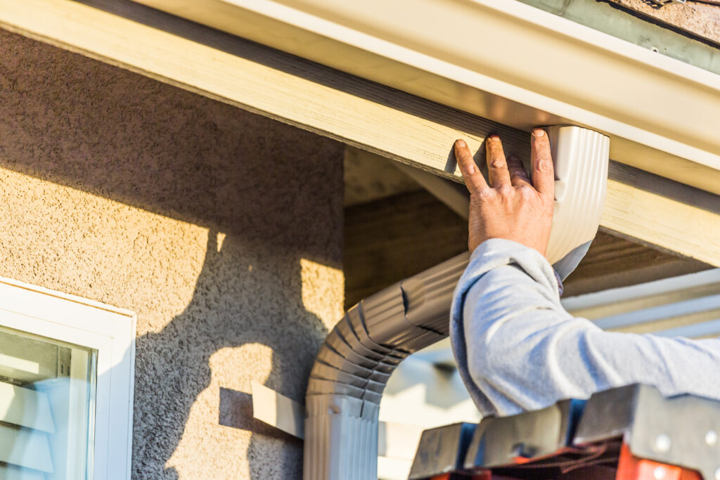 worker-attaching-aluminum-rain-gutter-and-down-spo